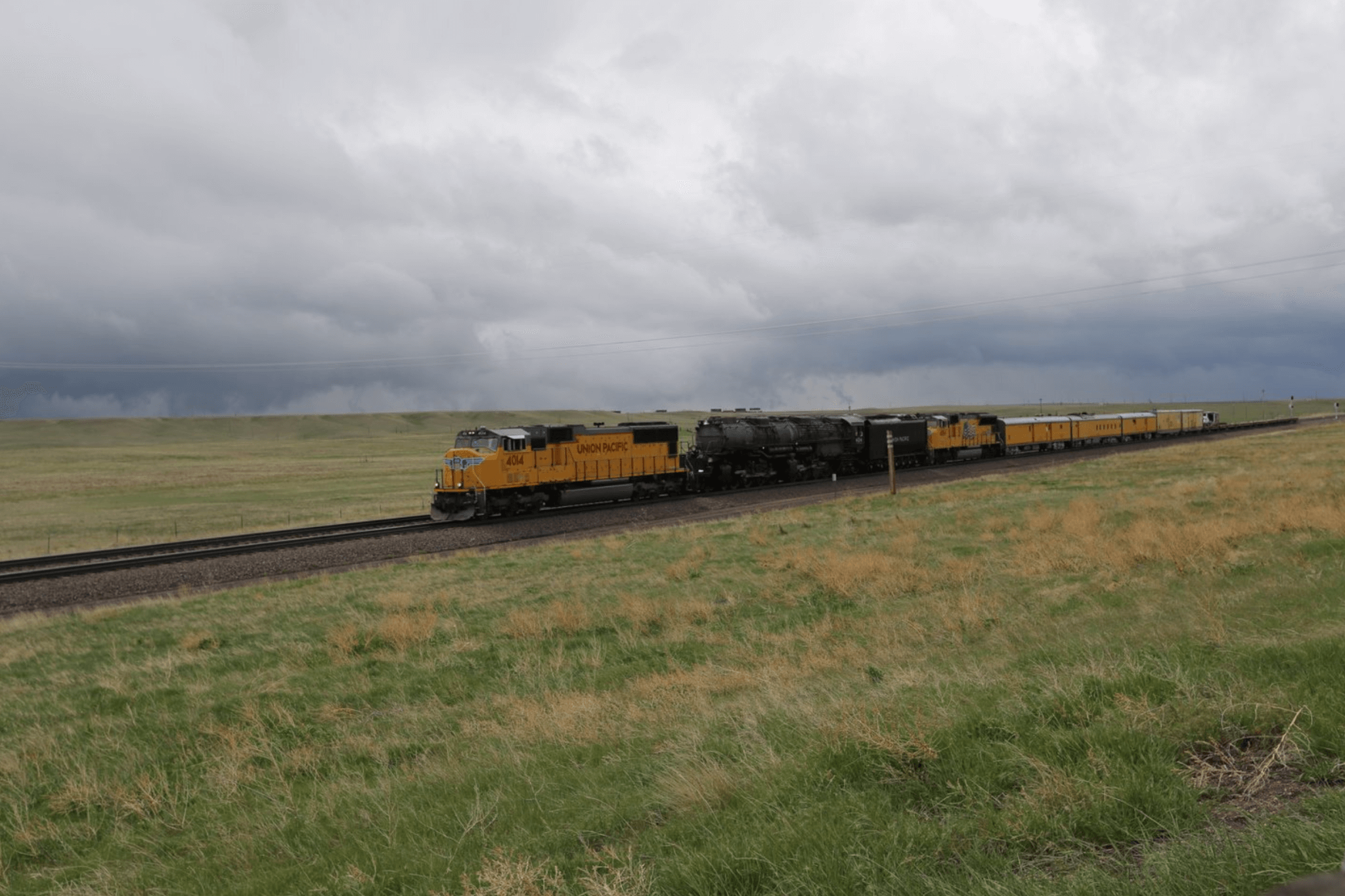 A train moves along a railroad on a hazy, cloudy day, rolling through a sprawling landscape.